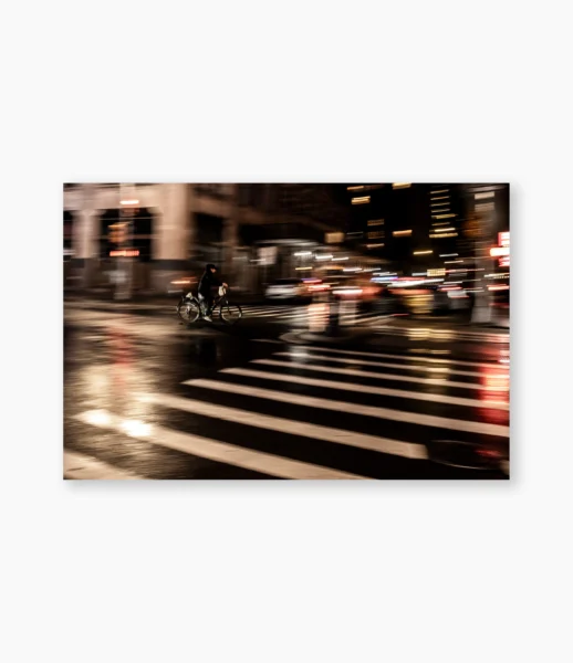Ciclista entre prédios com luzes em movimento, Nova York – fotografia de André Nunez