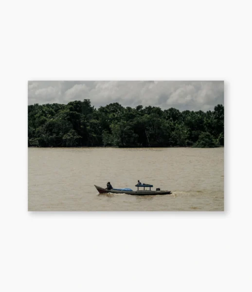 Pequeno barco atravessando rio largo diante da floresta amazônica – fotografia de André Nunez