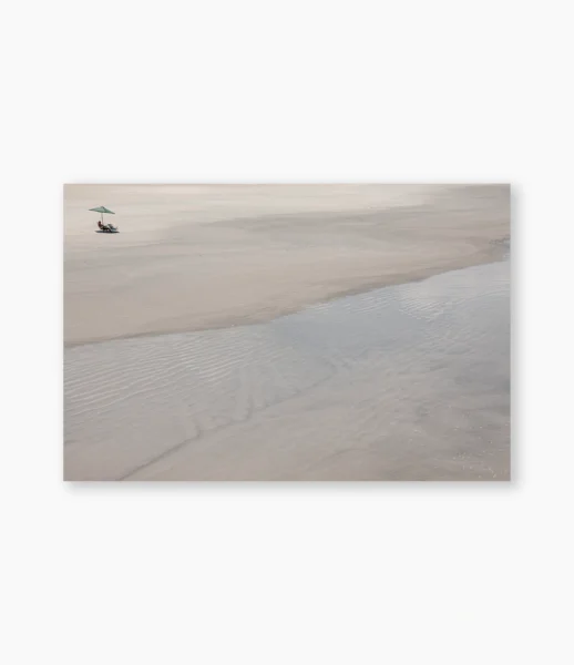 Guarda-sol solitário na praia com linhas de água na areia – fotografia de André Nunez