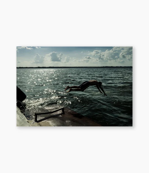 Pessoa mergulhando de um barco no rio ao sol da tarde, Belém do Pará – fotografia de André Nunez