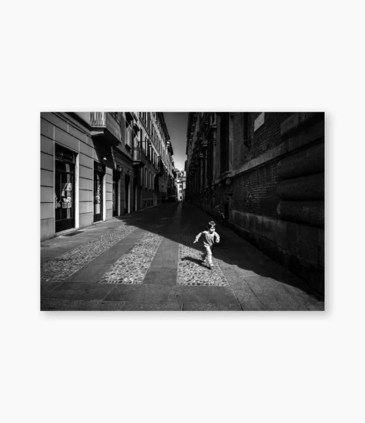 Menino atravessando rua entre edifícios históricos de Paris – fotografia de André Nunez