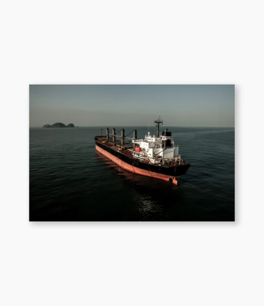 Embarcação de casco vermelho e ilha ao fundo sobre água parada – fotografia de André Nunez