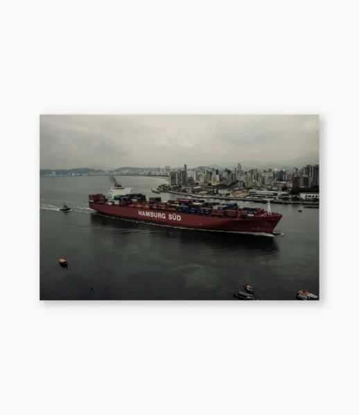 Navio entrando na baía com a cidade ao fundo sob céu carregado – fotografia de André Nunez