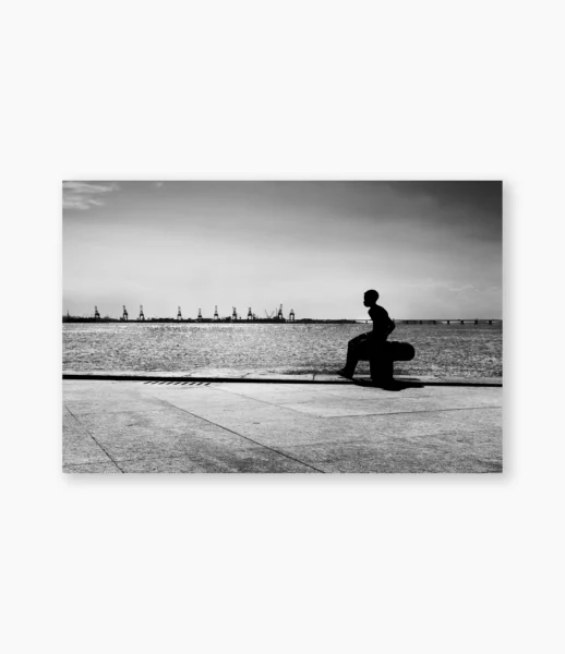 Menino sentado diante da Baía de Guanabara, Rio de Janeiro – fotografia de André Nunez